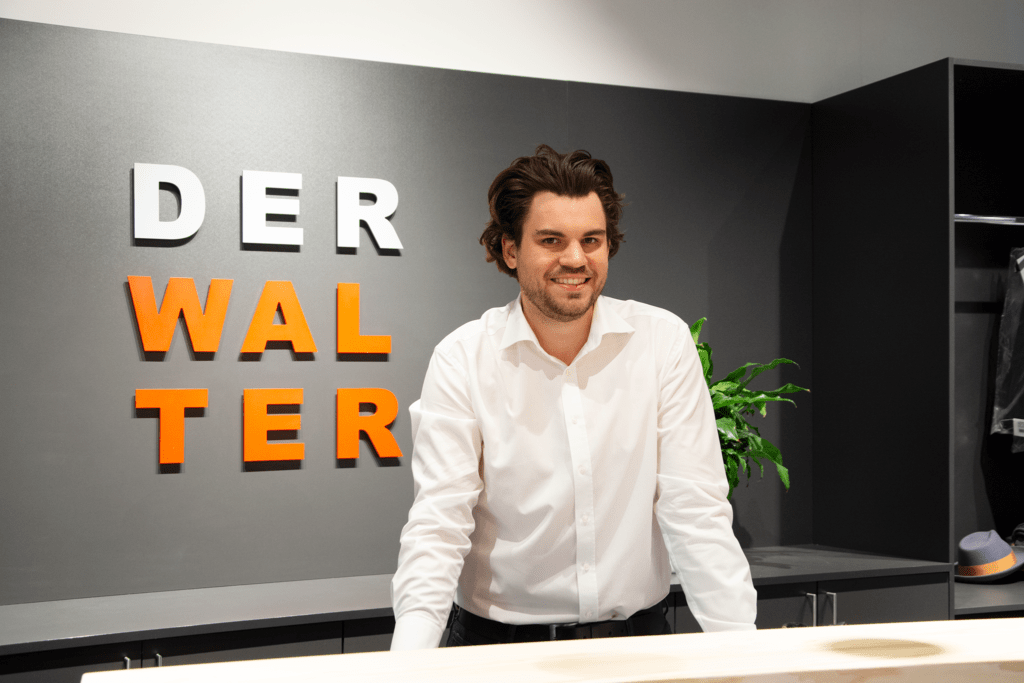 Junior-Chef Alexander Walter am Verkaufsthresen mit dem Firmenlogo im Hintergrund