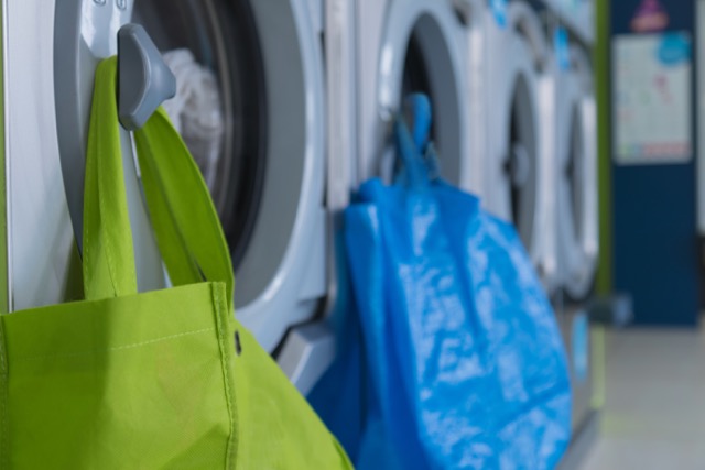 Detailaufnahme Waschmaschinen mit einem grünen und einem blauen Wäschesack im Green&Clean Shop.